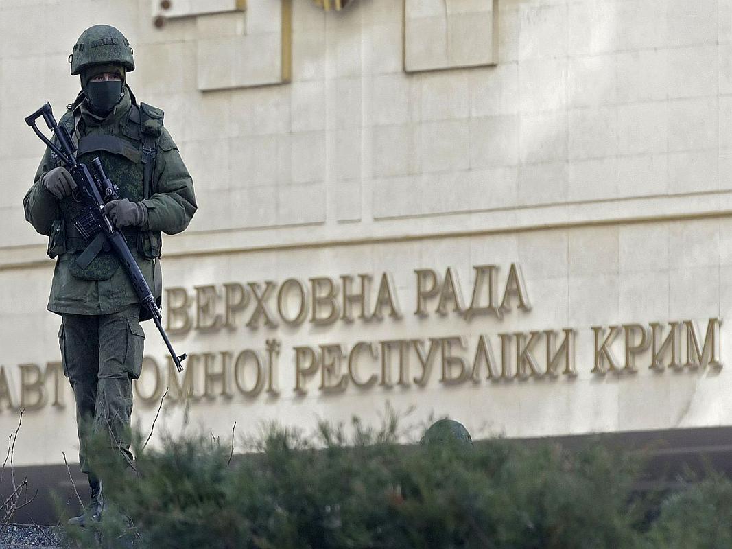 Oborožen moški pred poslopjem parlamenta krimske avtonomne pokrajine.