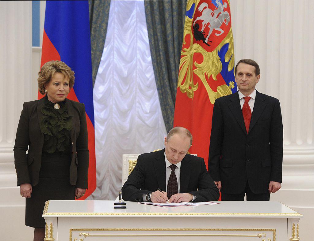 še zadnji podpis. Ob Putinu stojita predsednika obeh domov parlamenta, Sergej Nariškin in Valentina Matvijenko. Foto: Reuters