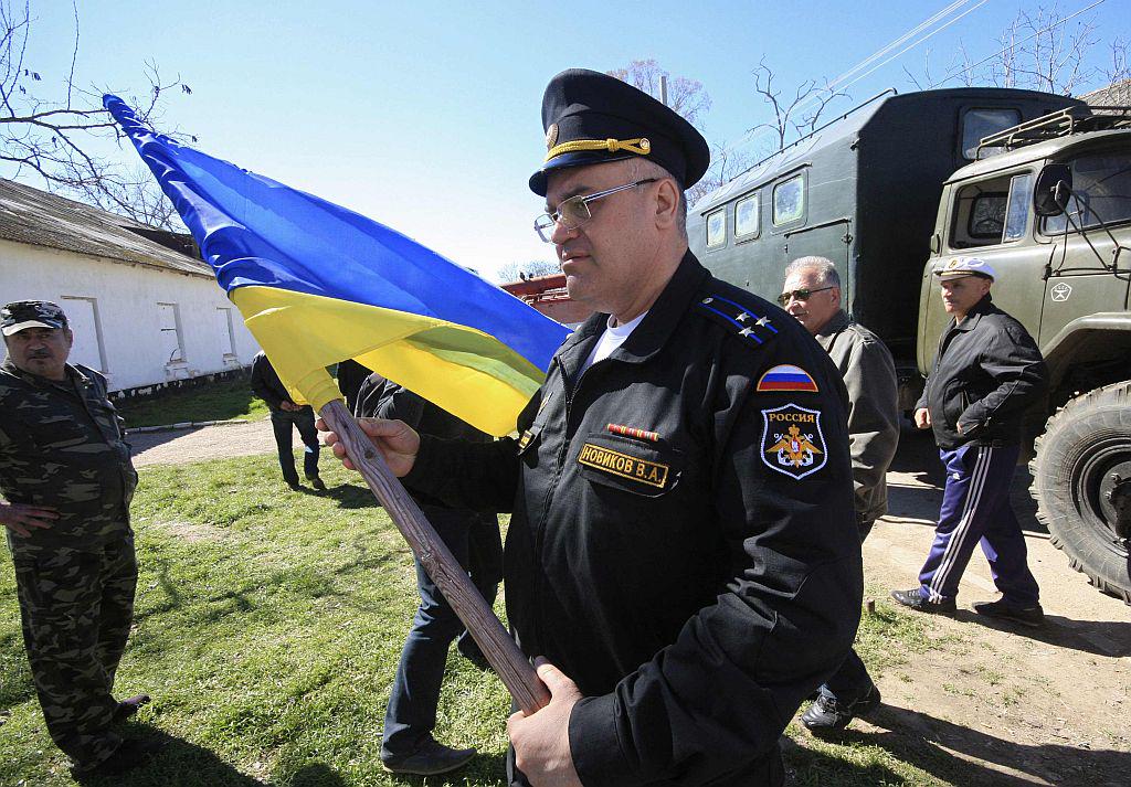 Ruski vojaški uradnik je s stavbe v Novofedorovki odstranil ukrajinsko zastavo. Foto: Reuters