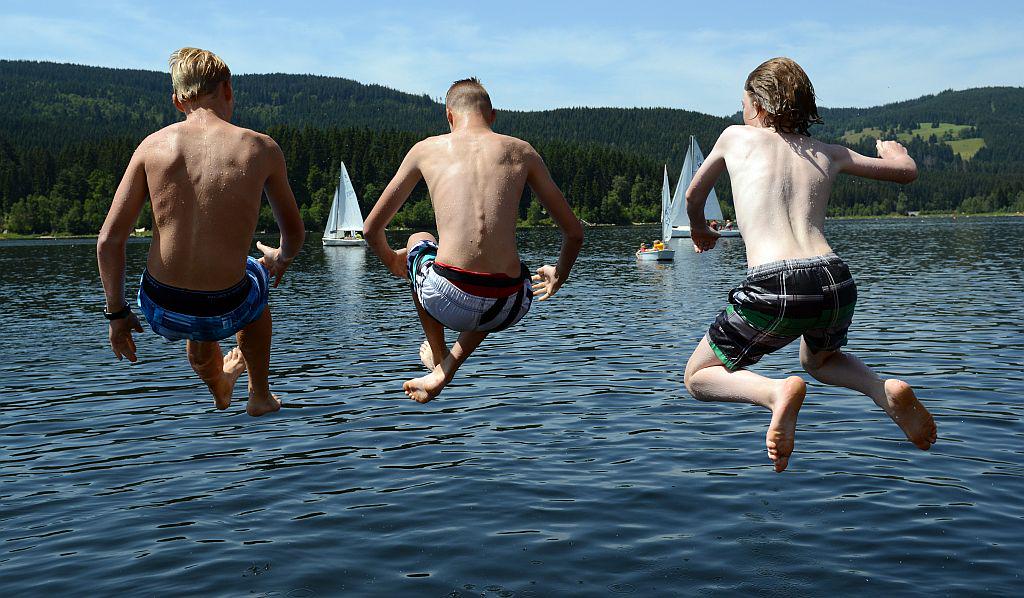 Trije fantje skačejo na noge v jezero. Foto: EPA