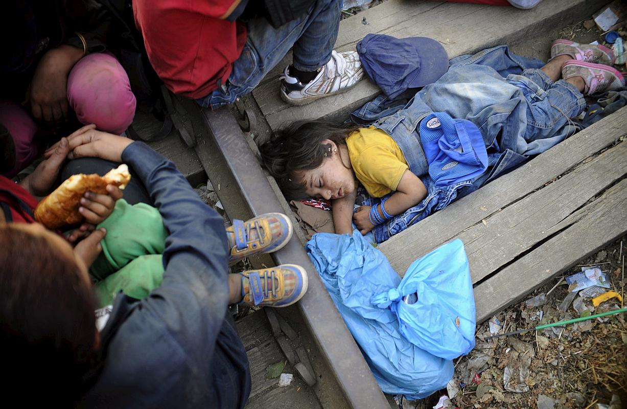 Deklica spi na tleh med železniškimi tiri v bližini postajališča Gevkelija. Foto: Reuters