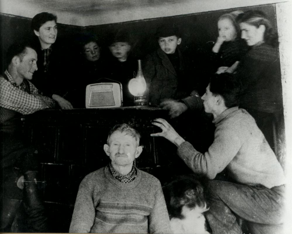 Vsi zbrani okoli radijskega sprejemnika poslušajo najnovejše vesti. Prve dni po koncu 2. svetovne vojne leta 1945. Foto: Muzejska zbirka RTV SLO