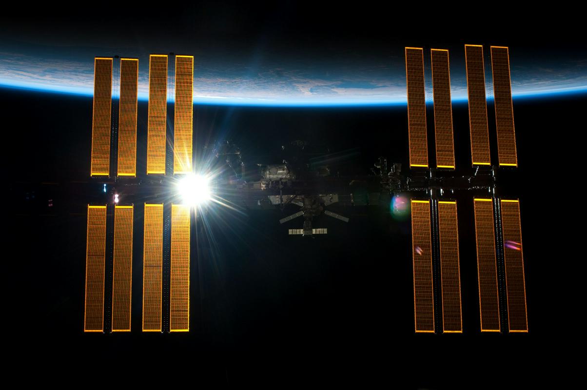 Mednarodna vesoljska postaja s Soncem v ozadju, ki osvetljuje panele sončnih celic. Foto: Nasa