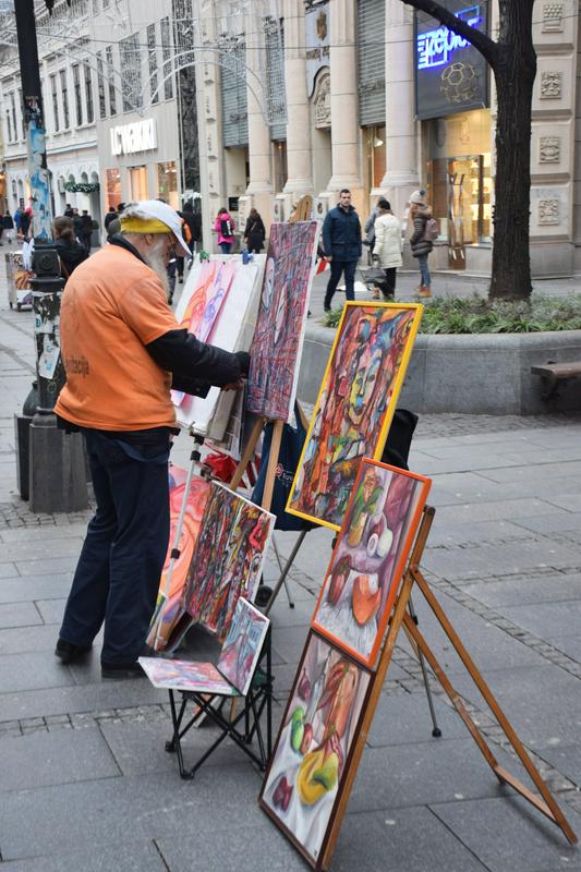 Ulični slikar in njegove umetnine, ki jih ponosno predstavlja na ulici Knez Mihailova, Beograd. Foto: Matic in Carmen Pirc