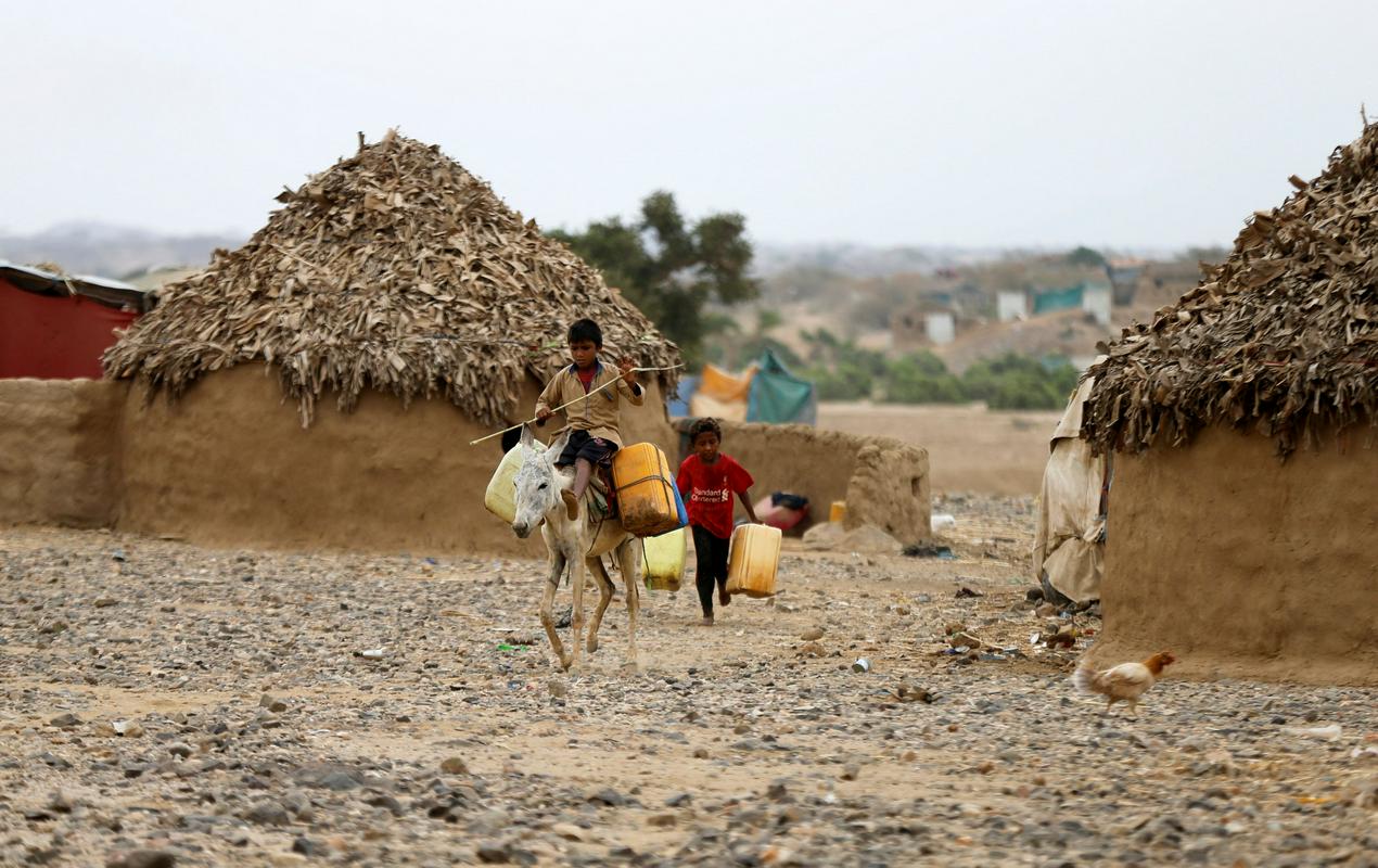Več kot tri milijone Jemencev je notranje razseljenih. Na fotografiji prizor iz improviziranega begunskega taborišča blizu Absa v severozahodni pokrajini Hadždža: dečka nosita vodo. Foto: Reuters