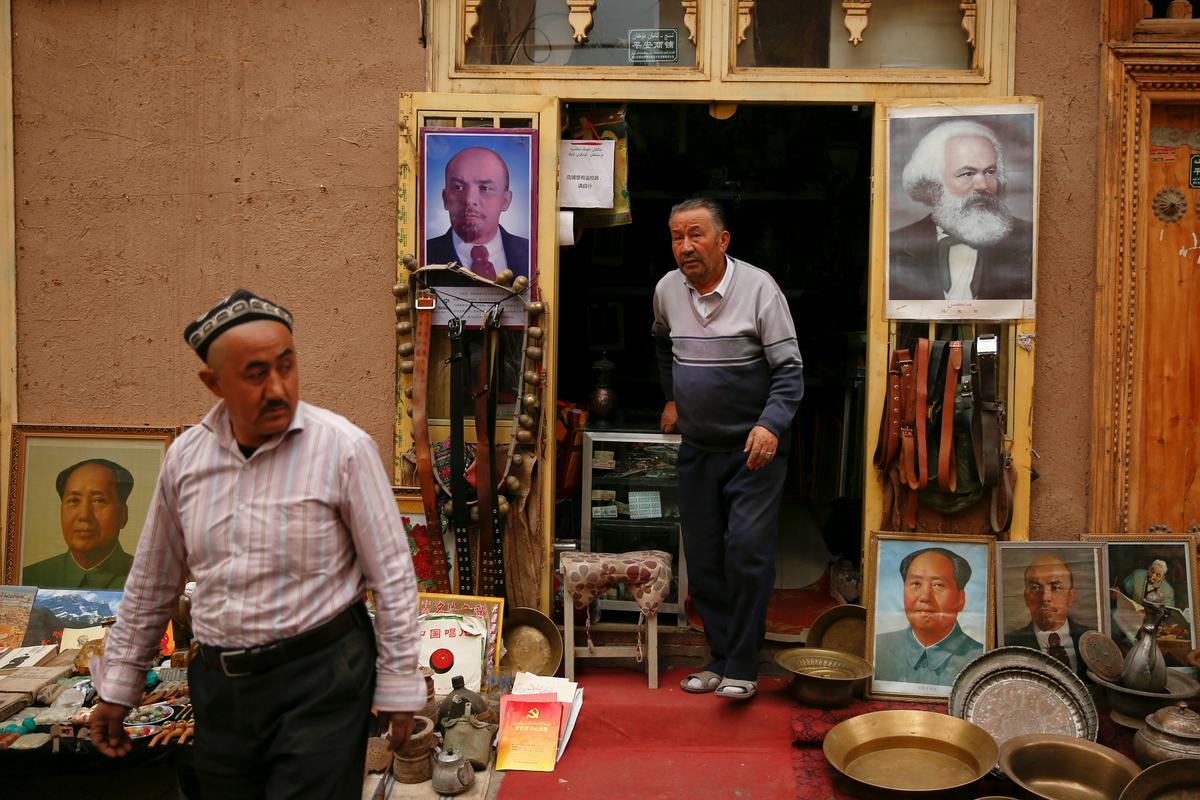 Portreti Mao Cetunga, Vladimirja Lenina in Karla Marxa pred ujgursko trgovino. Številne prodajalne z islamskimi spominki so se v zadnjih letih preusmerile.  Foto: Reuters