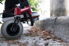 Opis fotografije: Na sliki je del invalidskega vozička, desno kolo in noga ter robnik, ki je lahko za nekoga na vozičku tudi nepremostljiva ovira. Foto: Matej Pušnik, arhiv MMC RTV SLO