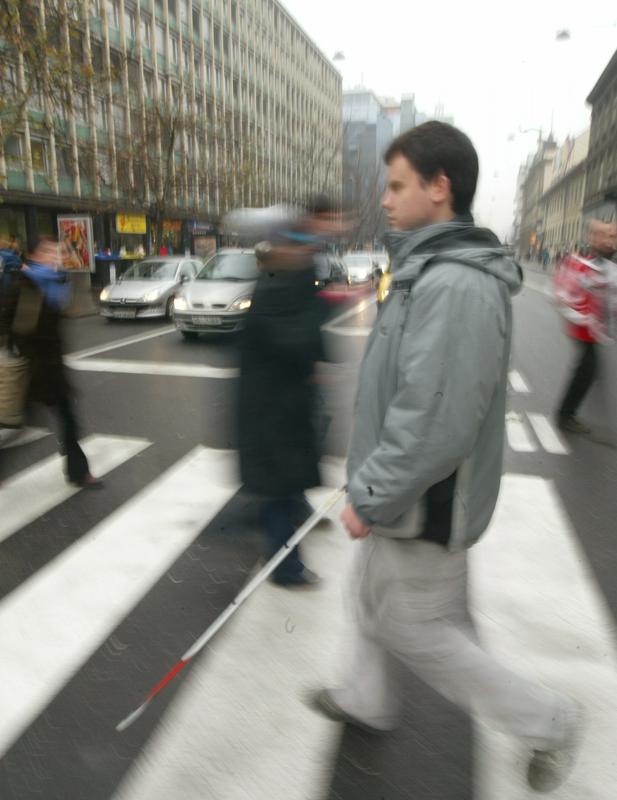 Opis fotografije: Na prehodu za pešce med ljudmi tudi slep fant z belo palico. Foto: BoBo, arhiv MMC RTV SLO