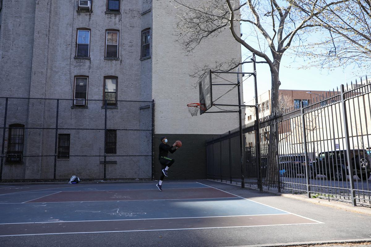 Osamljeni košarkar na enem izmed igrišč v New Yorku. Zvezna država New York je s približno 39.000 potrjenimi okužbami z novim koronavirusom središče epidemije v ZDA. V samem mestu je potrjenih nekaj več kot 23.000 okužb. Foto: Reuters