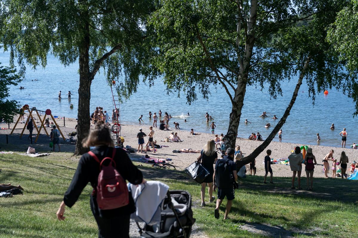 Kopalci na jezeru Malaren v Stockholmu. Švedska vlada je prebivalce zgolj pozvala, naj upoštevajo priporočila o medosebni razdalji. Za restavracije in bare so uvedli nekoliko spremenjena pravila, kot je denimo sedenje med prehranjenvanjem. Foto: Reuters