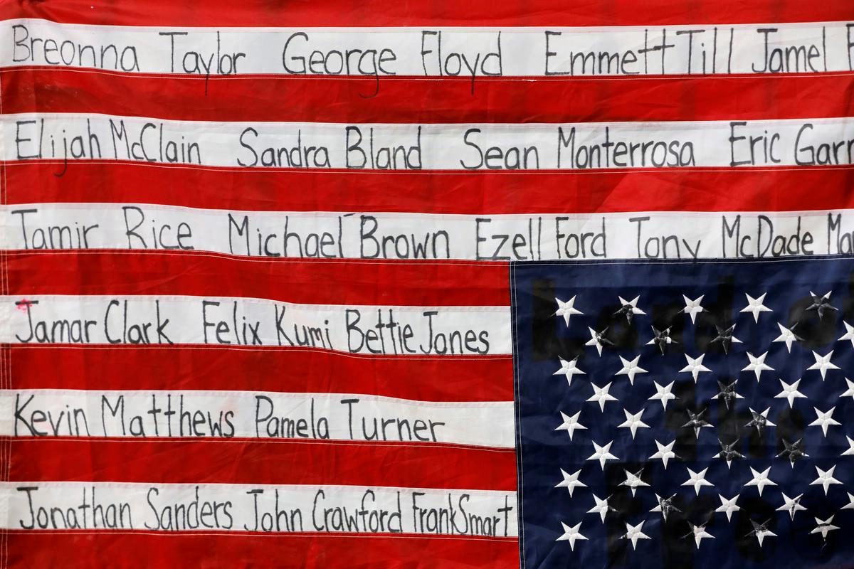 Narobe obrnjena ameriška zastava z imeni nekaterih temnopoltih Američanov, ki jih je ubila policija. Foto: Reuters