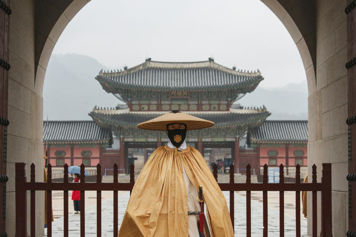 V tradicionalnem kostumu in maski pred templjem v Južni Koreji. Foto: Reuters