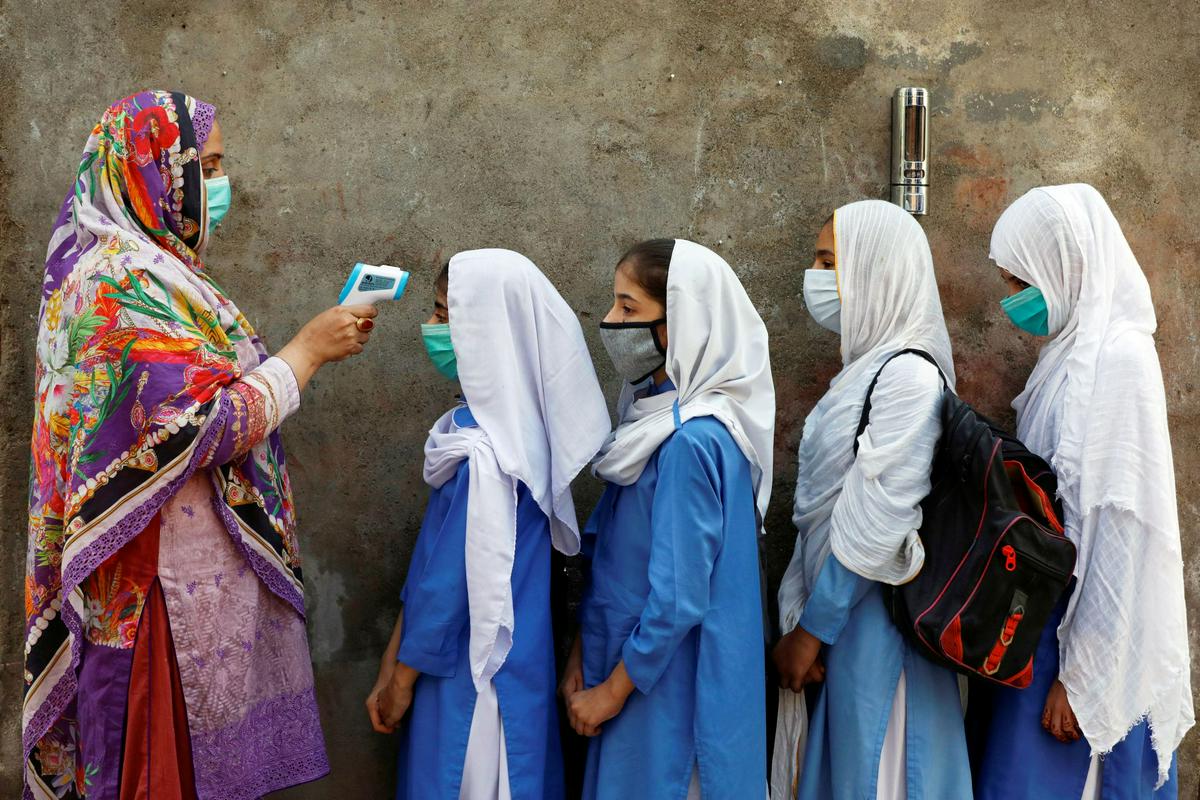 Merjenje temperature je postalo eden izmed običajnih ukrepov povsod po svetu. Prizor je iz indijske šole. Foto: Reuters