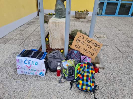 Starši z odlaganjem torb pred zaprtimi šolskimi vrati izražajo nestrinjanje z vladnimi odločitvami. Foto: Marko Štor/TV Slovenija