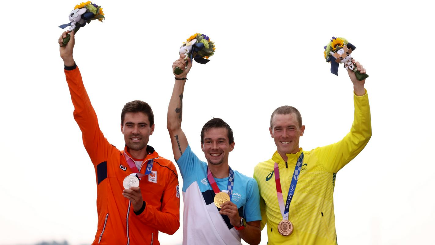 Primož Roglič je postavil nov mejnik slovenskega kolesarstva! Dobil je zlato olimpijsko medaljo. Družbo na odru za zmagovalce sta mu delala še Nizozemec Tom Dumoulin in Avstralec Rohan Dennis. Foto: Reuters