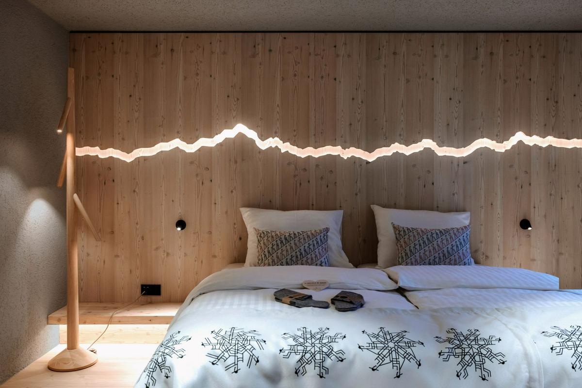 Nad posteljami je izdolbena podoba slovenskih gora. Potisk na posteljnini je iskal navdih v štirih Srčnih možeh. Foto: Žiga Intihar