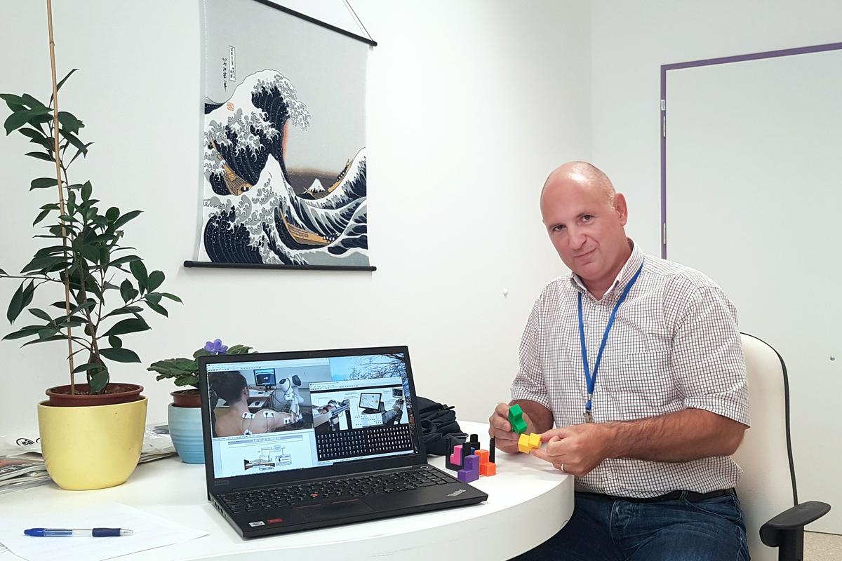 Dr. Imre Cikajlo v pisarni. Na mizi je računalnik s fotografijami različnih tehničnih rešitev. Foto: URI Soča