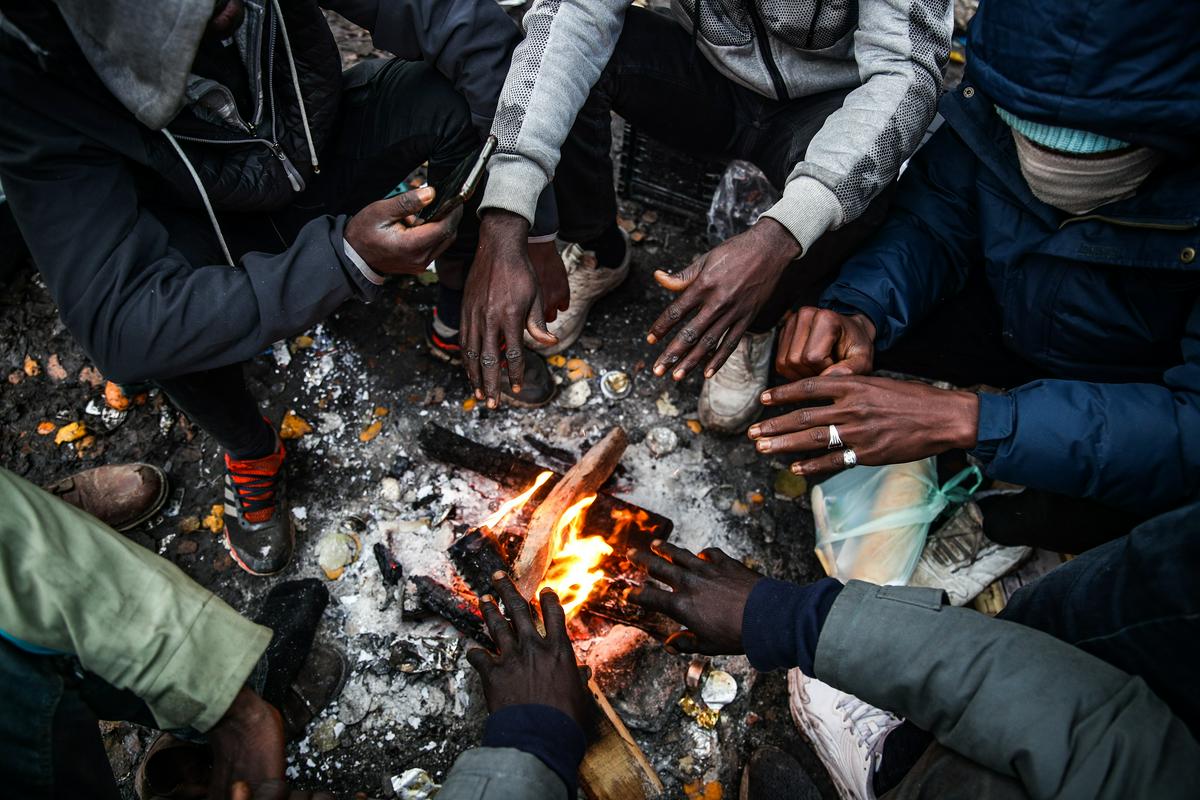 Prebežniki iz Sudana, ki se grejejo v šotorišču v Calaisu. Foto: EPA