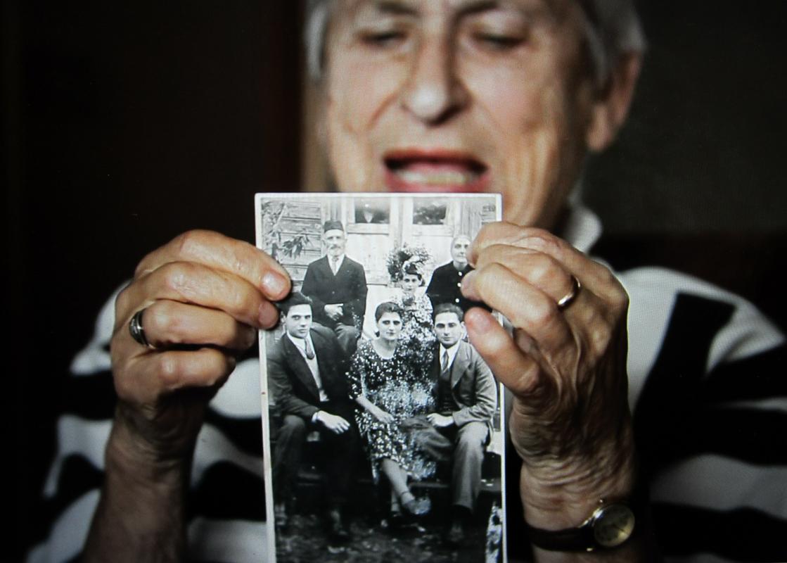 Fania Yocheles - Brancovskaya, 99 let (Litva). Preživela je geto v Vilni, med drugo svetovno vojno se je pridružila partizanom v gozdu Rudninkai. Na fotografiji kaže Fania sliko svoje družine med  intervjujem za državni judovski muzej Vilna Gaon. 2016, Litva. Foto: Neringa Latvyte, zasebna zbirka. 