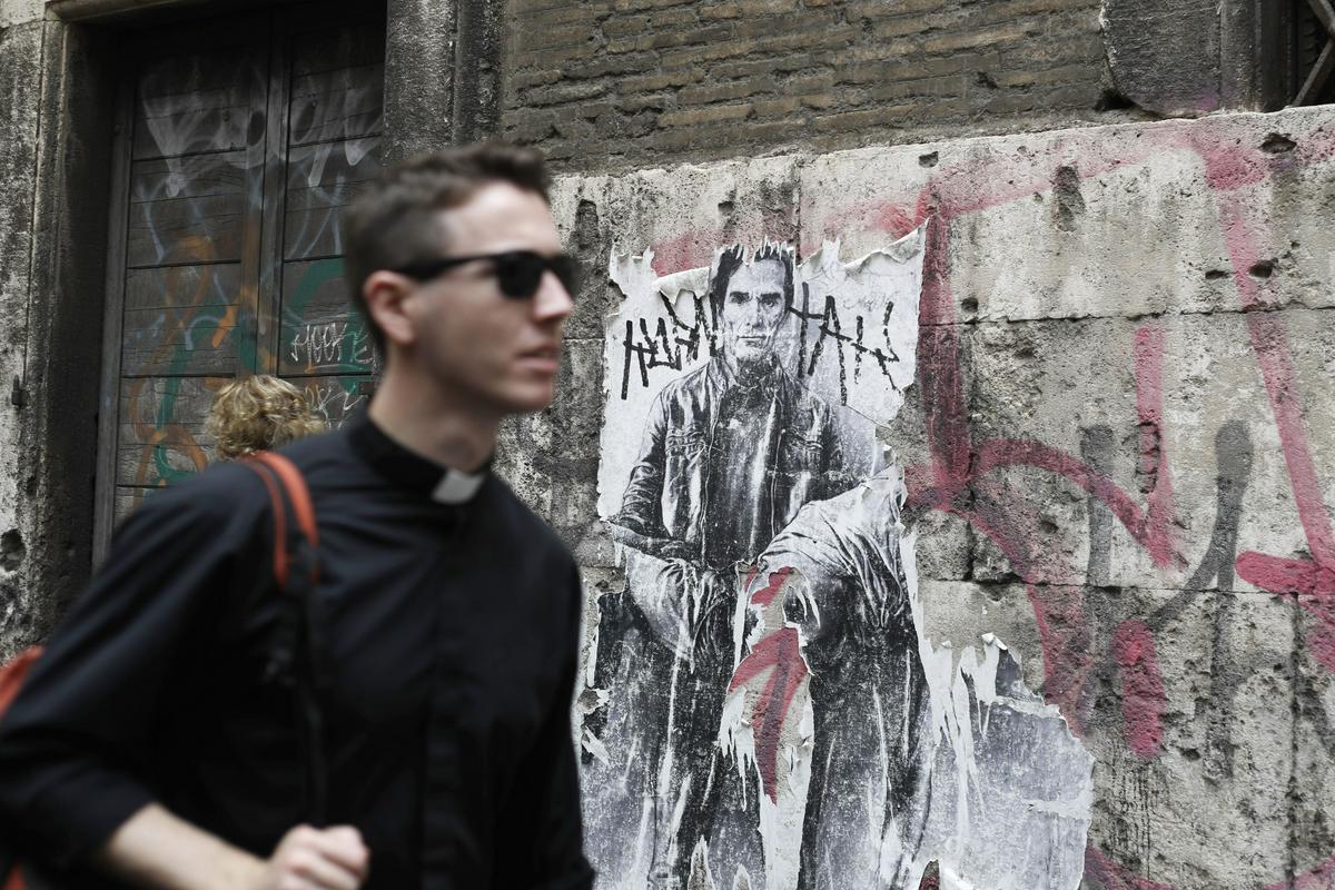 Utrinek iz sodobnega Rima: v ospredju mlad duhovnik, v ozadju ulična umetnost s podobo Pasolinija. Foto: AP