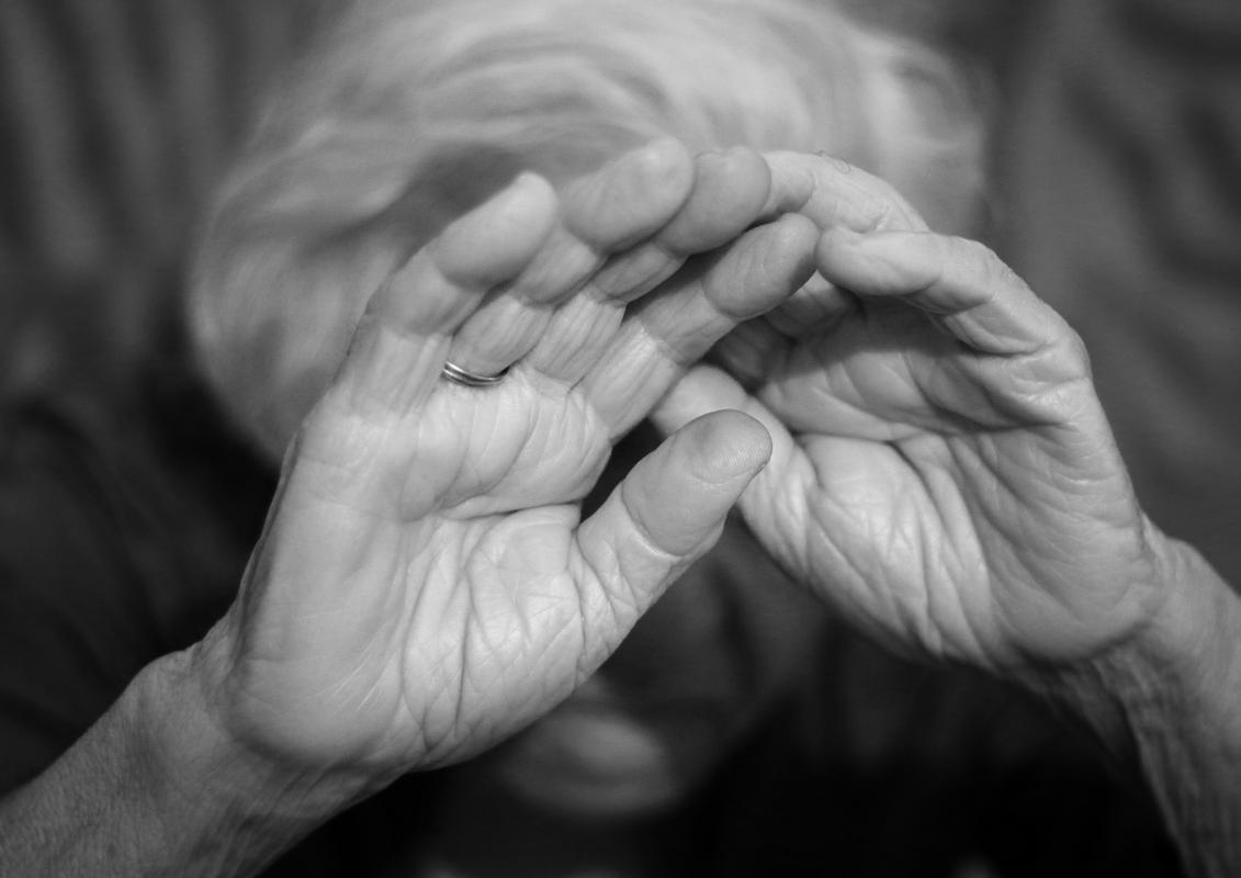 Na fotografiji je starejša oseba, ki drži roke pred obrazom. Izgleda, kot da se brani pred nasiljem. Foto: Shutterstock