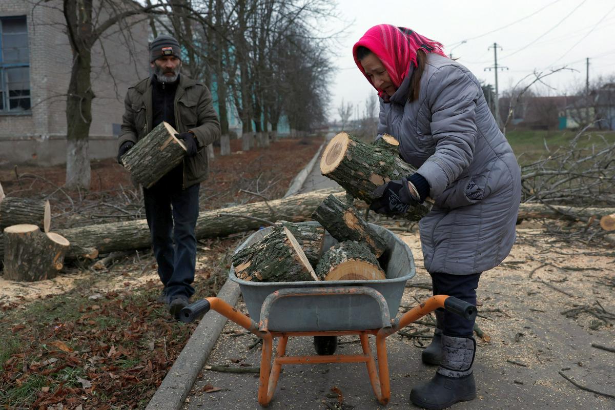 Prebivalci Bahmuta na vzhodu Ukrajine, kjer divjajo najhujši spopadi med ruskimi in ukranjinskimi silami, za kurjavo sekajo drevesa v mestu. Foto: Reuters
