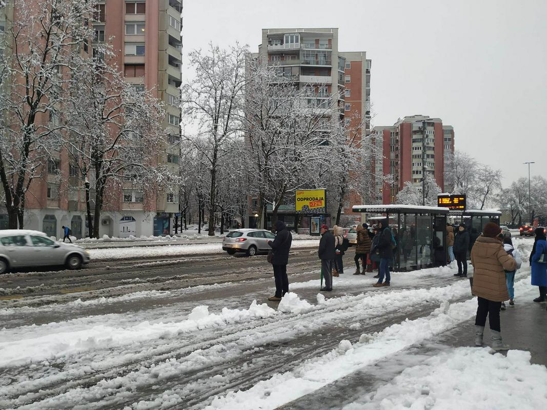 Na sliki je postajališe Ljubljanskega potniškega prometa v Šiški v Lubljani. Na postajlišču je sneg. Prav tako so kupi snega na delno očiščenem pločniku ob postojališču. Foto: MMC RTV SLO