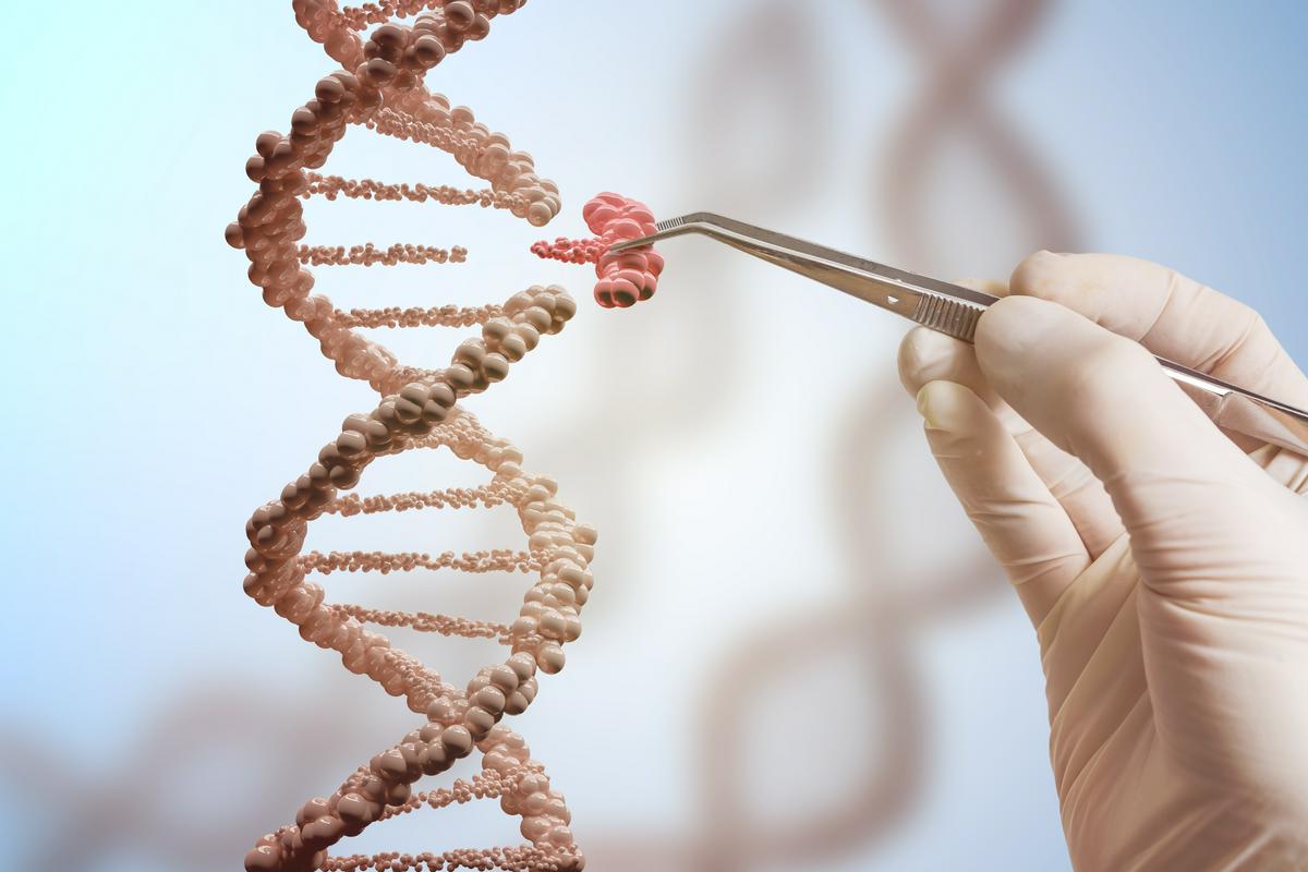 Prekinjena veriga DNK, v katero nekdo vstavlja manjkajoči delček genskega zapisa. V dlani, oblečeni v rokavico, med prsti drži pinceto. Foto: Shutterstock
