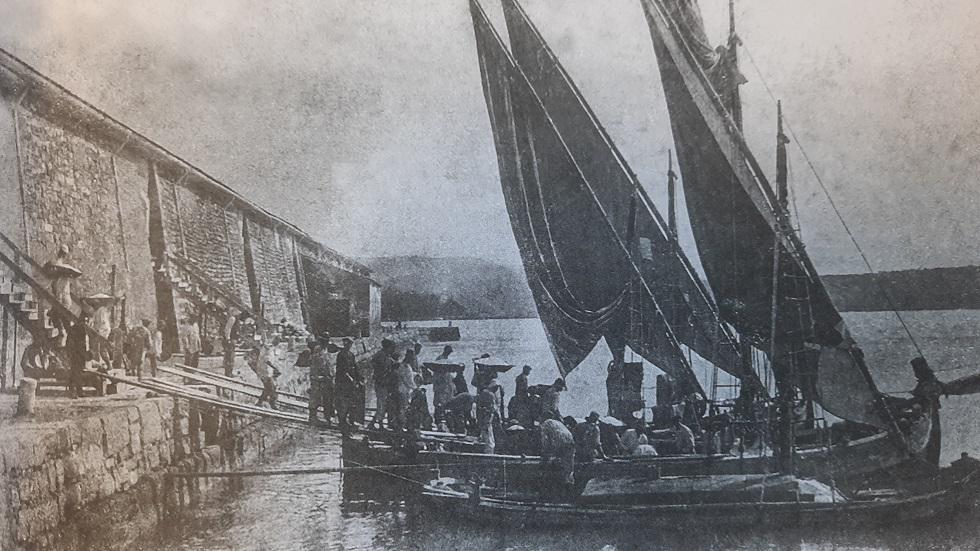 Črno bela fotografija iz monografije Solinska plovila, ki prikazuje praznjenje štirih barkinov pred skladiščem Grando. Foto: dLib