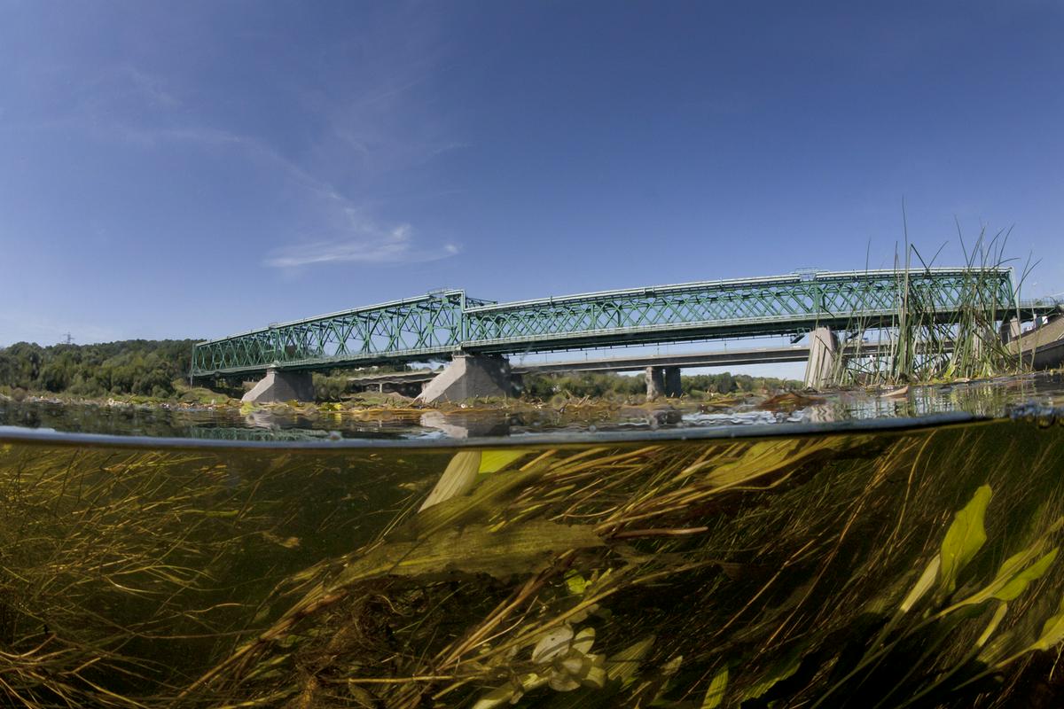 Nemen je največja vzhodnoevropska reka. Izvira v Belorusiji, teče skozi Litvo in ob litovski meji z rusko Kaliningrajsko oblastjo in se pri otoku Rusne izliva v Baltsko morje. Na fotografiji je ujeta pod mostom v mestu Kaunas v Litvi. Foto: Cankarjev dom/Andreas Müller-Pohle