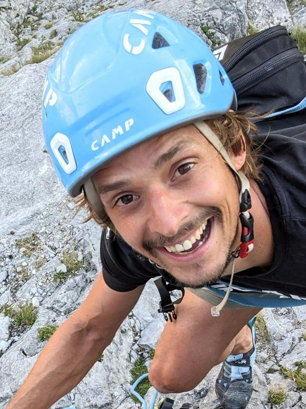 Na fotografiji je Gregor Selak. Nasmejan pleza po skalah in ima na glavi modro plezalno čelado. Foto: Osebni arhiv Gregorja Selaka