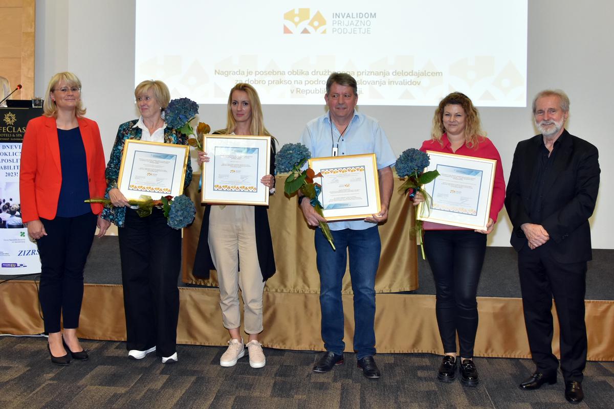 Z leve proti desni Andrejka Znoj, štirje predstavniki podjetij, ki so prjeli nagrade za za dobro prakso pri zaposlovanju invalidov za leto 2022 in Karel Destovnik. Nagrajenci v rokah držijo priznanja in rože. Foto: Arhiv ZIZRS