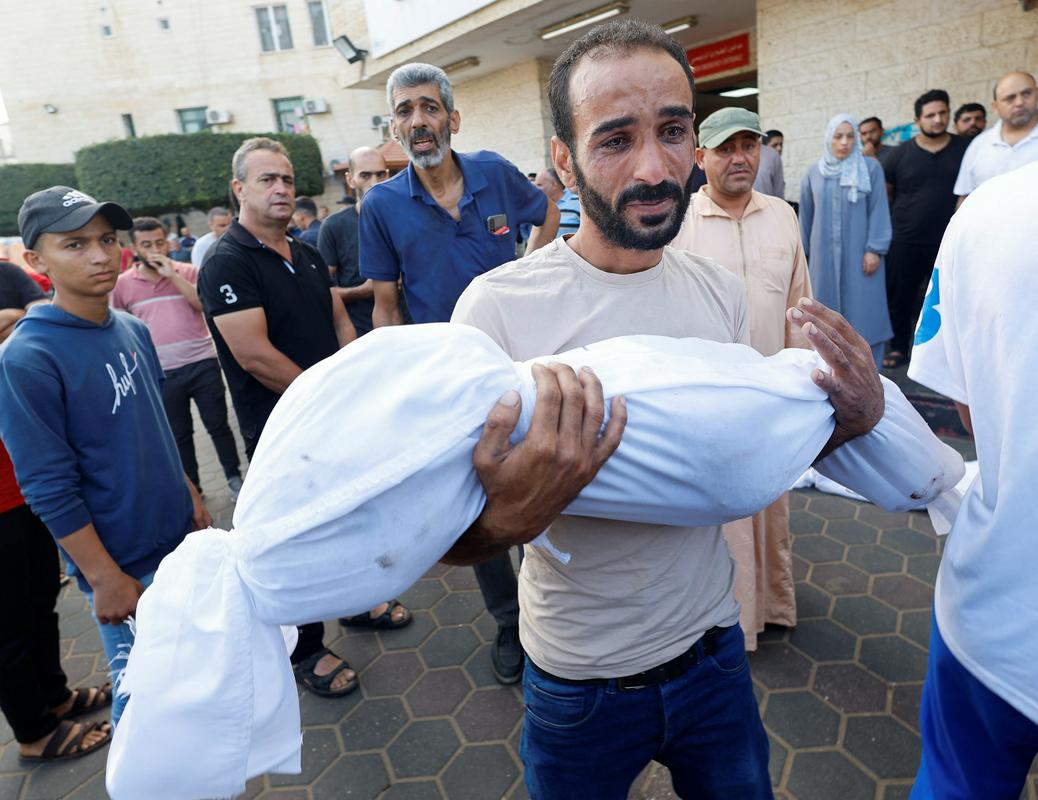 Palestinski oče v Gazi s truplom svojega otroka po zračnih napadih Izraela. Foto: Reuters
