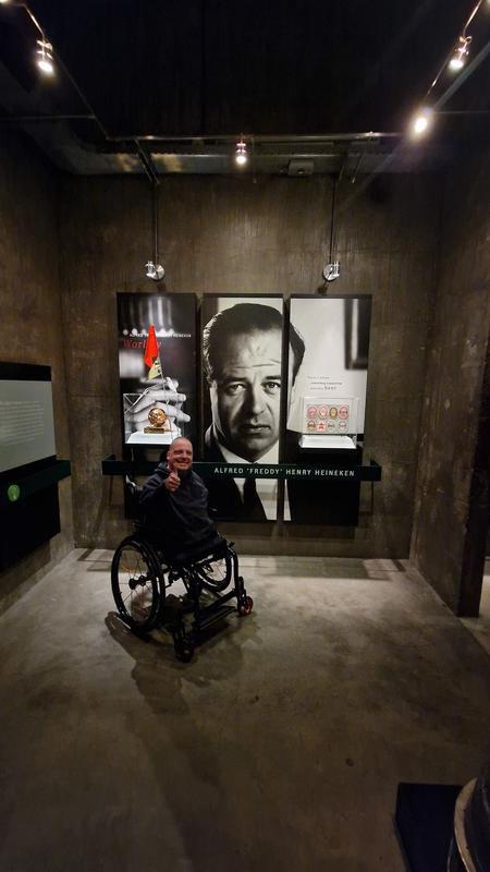 Miha Nardoni v muzeju Heiniken v Amsterdamu. Z vozičkom se je postavil pred platno na katerem je fotografija Alfreda Henikena in dvignil palec na roki. Foto: Osebni arhiv