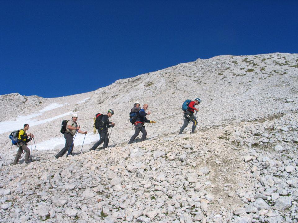 Pet pohodnikov s palicami se vzpenja po melišču proti Triglavu. Drugi v vrsti v nahrbtniku nosi Miha Nardonija. Foto: Osebni arhiv