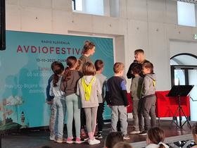 Ajda Smrekar in otroci iz OŠ Poljane na Avdiofestivalu 2025. Foto: Tanja Mojzer