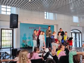 Ajda Smrekar in otroci iz OŠ Poljane na Avdiofestivalu 2025. Foto: Tanja Mojzer
