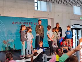 Ajda Smrekar in otroci iz OŠ Poljane na Avdiofestivalu 2025. Foto: Tanja Mojzer