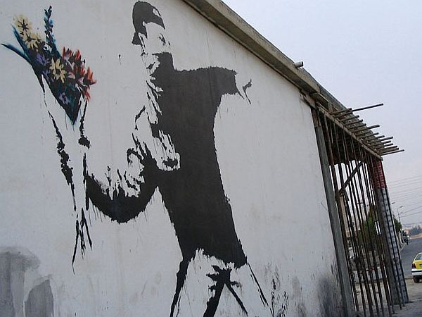 Banksy je Metalca rož (Flower Thrower, Flower Bomber, Rage ali Love is in the Air) ustvaril leta 2003 v palestinskem mestu Beit Sahour na Zahodnem bregu in velja za eno njegovih najznamenitejših del. Foto: EPA